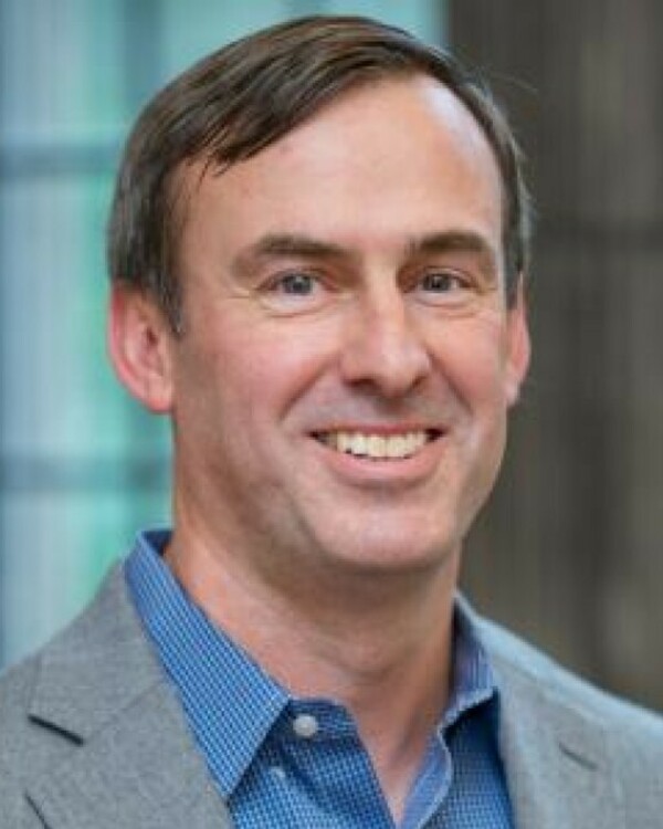 Man smiling wearing blue shirt and grey jacket